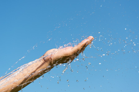 Water and hand against blue sky.の写真素材