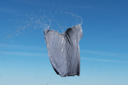 Wet gray shirt flying in blue sky.の写真素材