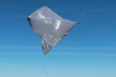 Wet gray shirt flying in blue sky.の写真素材