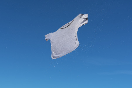 Wet gray shirt flying in blue sky.の写真素材