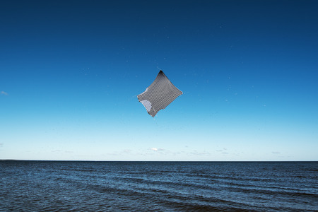Striped shirt flying above blue sea.の写真素材