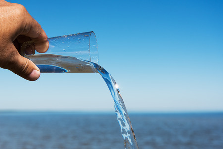 Glass of water and sea.の写真素材