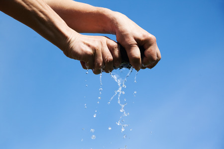 Squeezing if cloth against blue sky.の写真素材