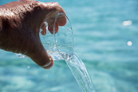 Pouring water in glass against nature background.の写真素材