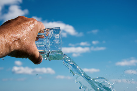 Pouring water in glass against nature background.の写真素材