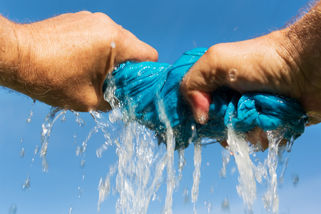 Mans hands  squeeze out wet fabric.の写真素材