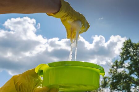 Hands in yellow protective gloves squeeze yellow rag.の写真素材