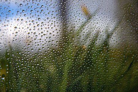Water drops on window and rural landscape.の写真素材
