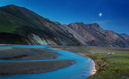 Night view of a colorful mountain ridge and river flowing down in the valley with sheep eating grass, Landmannalaugar, Icelandの写真素材