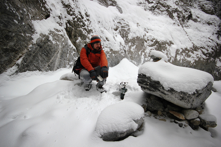 Young man making a hot coffee in mountains back country during freezing and snowy day - concept of camping, traveling, adventureの写真素材