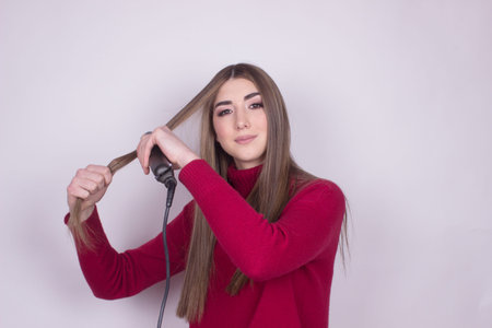 attractive young beautiful girl using hair iron