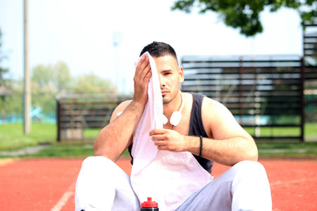 tired man wiping sweat after runningの写真素材