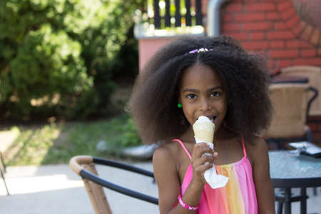 cute mixed girl eating an ice creamの写真素材