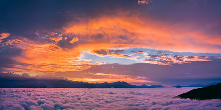 Bright and colorful sunset over the sea of clouds. Panoramic view in violet orange and pink colors.の写真素材