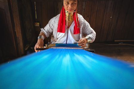 YWAMA VILLAGE/MYANMAR - FEBRUARY 2014 - A woman from the Padaung tribe, commonly referred to as the Long Neck tribe is weaving at house in Ywama village, Inle Lake, Myanmar in February, 2014.のeditorial素材