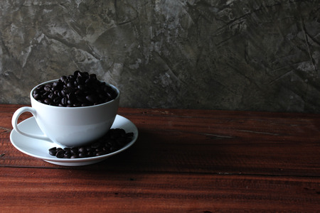 Coffee beans in a cup on a wooden floor.の写真素材