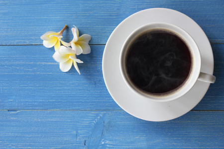 Hot coffee on a blue wooden floor With frangipani flowers, on top view.の写真素材