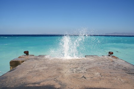 Wave splashing on a stone jetty in the Mediterranean Seaの写真素材