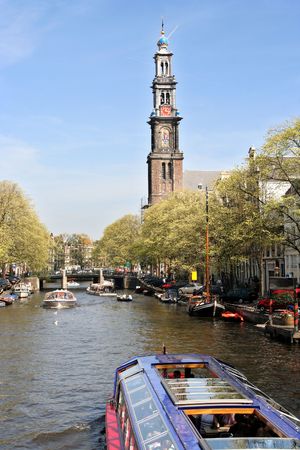 Amsterdam canal with tour boats and the tower of the Westerchurch in the backgroundの写真素材