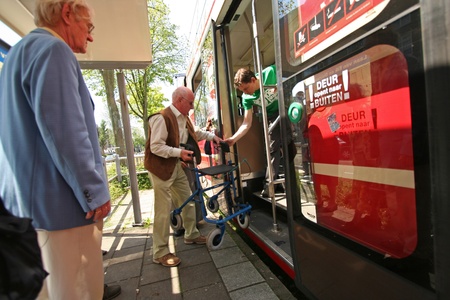 Young man assists old people with walker entering a tram on May 31, 2009 in The Hague, Hollandのeditorial素材