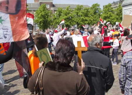 THE HAGUE, HOLLAND - MAY 19: Syrian woman holds up the Koran and the Christian cross at a demonstration for Syria and Assad in the center of The Hague, Holland on May 19, 2012のeditorial素材