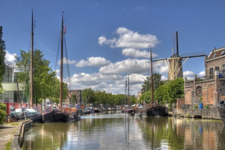 Windmill and historical boats in a canal in Gouda, Hollandの写真素材