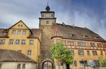 Ancient gate with clock tower and attached historical buildings in Rothenburg ob der Tauber, Germanyの写真素材