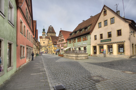 Rothenburg ob der Tauber, Germany - May 6, 2014: Historical street with people admiring the medieval architecture of houses and a clock tower gate in Rothenburg ob der Tauber, Germany on May 6, 2014.のeditorial素材