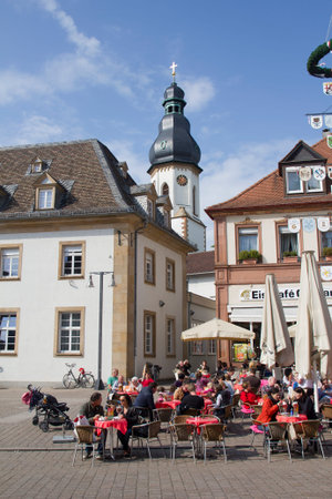 Speyer, Germany - May 2, 2014: Tourists sit in outdoor cafe in the mainstreet of Speyer, with historical buildings and a church tower in the old centre of Speyer, Germany on May 2, 2014のeditorial素材