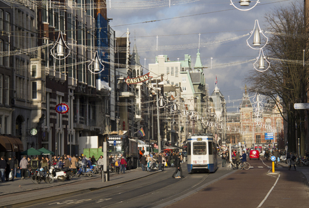 Amsterdam, Holland - November 12, 2015: People waiting at a street car stop in a major shopping street decorated for Christmas, with the railway station in the distance, on November 12, 2015 in Amsterdam, Holland.のeditorial素材
