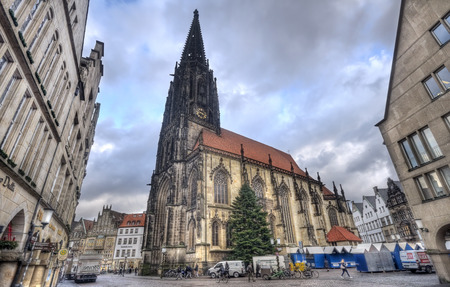 Munster, Germany - December 23, 2015: People walk in front of the Saint Lamberti church in the Prinzipalmarkt street with a christmas tree in Munster, Germany on December 23, 2015のeditorial素材