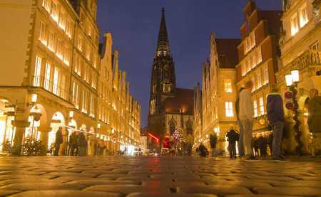 Munster, Germany - December 23, 2015: People walk in the evening in the Prinzipalmarkt street lined with historical buildings and the Saint Lamberti church and a chrismas tree in Munster, Germany on December 23, 2015のeditorial素材