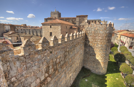 Ancient city walls and cathedral and trees and grass lawn in the old city of Avila, Spainの写真素材