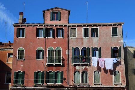 Washed clothes hang to dry from the windows of a historical building in Venice, Italyのeditorial素材