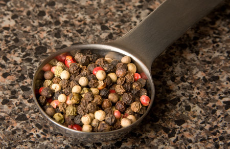 Measuring spoon with pepper corns in it.
