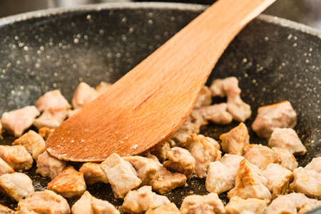 Cooking pork meat on frying pan with spatulaの写真素材