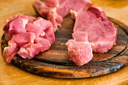 Raw sliced pork leg meat on wooden cutting board