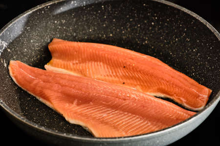 Cooking tasty and fresh rainbow "salmon" trout fish on frying panの写真素材