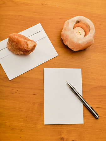 Paper, modern envelope, paperweight, candle and metal ballpoint on wooden tableの写真素材