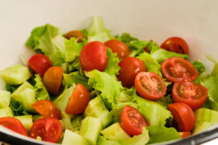 Fresh and tasty salad with cherry tomatoes and cucumber in white bowlの写真素材