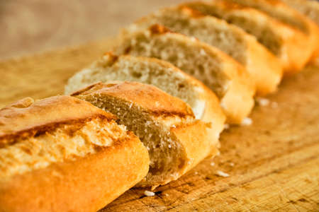 Tasty baquette cut on wooden cutting board close up detailの写真素材