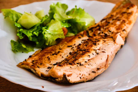 Tasty and fresh rainbow "salmon" trout fish fillet spiced on white table with green vegetablesの写真素材