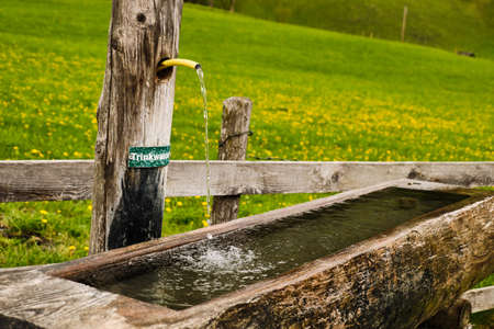 Wooden trough with trinkable water at the edge of Dorfgastein in springの写真素材