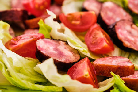 Tasty smoke-dried sausages with vegetable green salad and tomatoesの写真素材