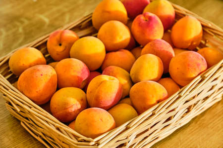 Tasty fresh apricot fruit in basket on wooden table close upの写真素材