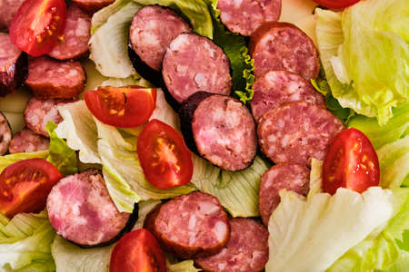 Tasty smoke-dried sausages with vegetable green salad and tomatoesの写真素材