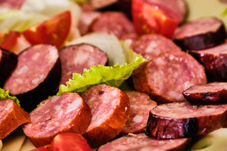 Tasty smoke-dried sausages with vegetable green salad and tomatoesの写真素材