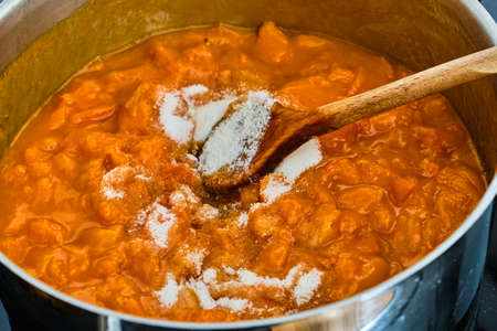 Stiring gelling sugar in white cooking tasty fresh apricots preparing homemade marmeladeの写真素材