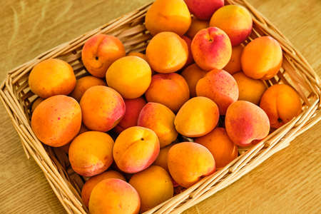 Tasty fresh apricot fruit in basket on wooden table close upの写真素材
