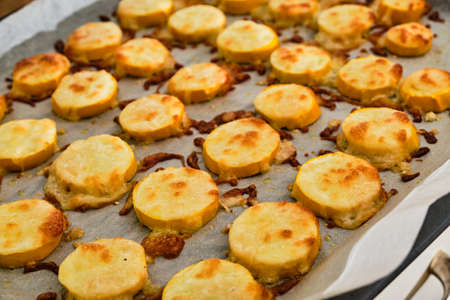 Tasty and fresh baked yellow zucchini with mozzarella and parmesan cheese on baking paperの写真素材